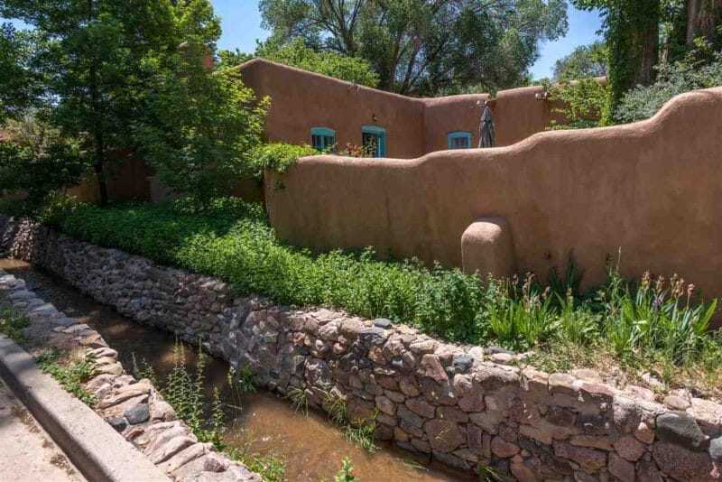 The Acequia Madre next to an adobe house