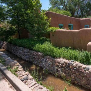 The Acequia Madre next to an adobe house