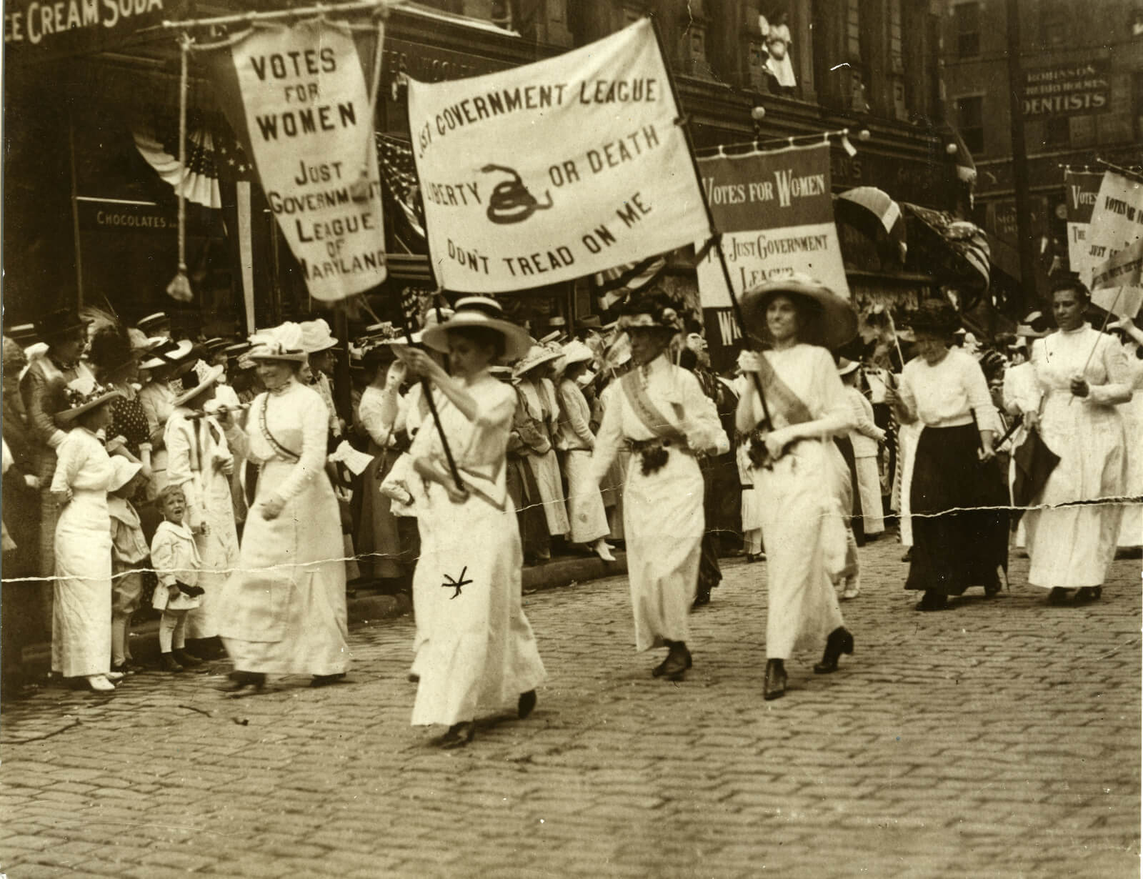 Black and white photo of women marching with large banners