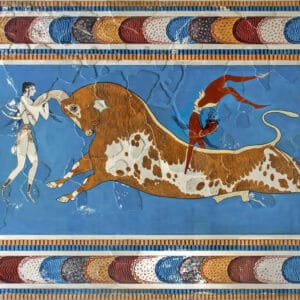 Photo of three figures leaping over a bull