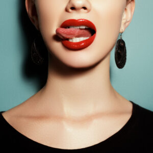 A model with one earring on a colorful background. Natural full lips with red lipstick and lip gloss